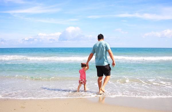 father and daughter holding hands walking on beach