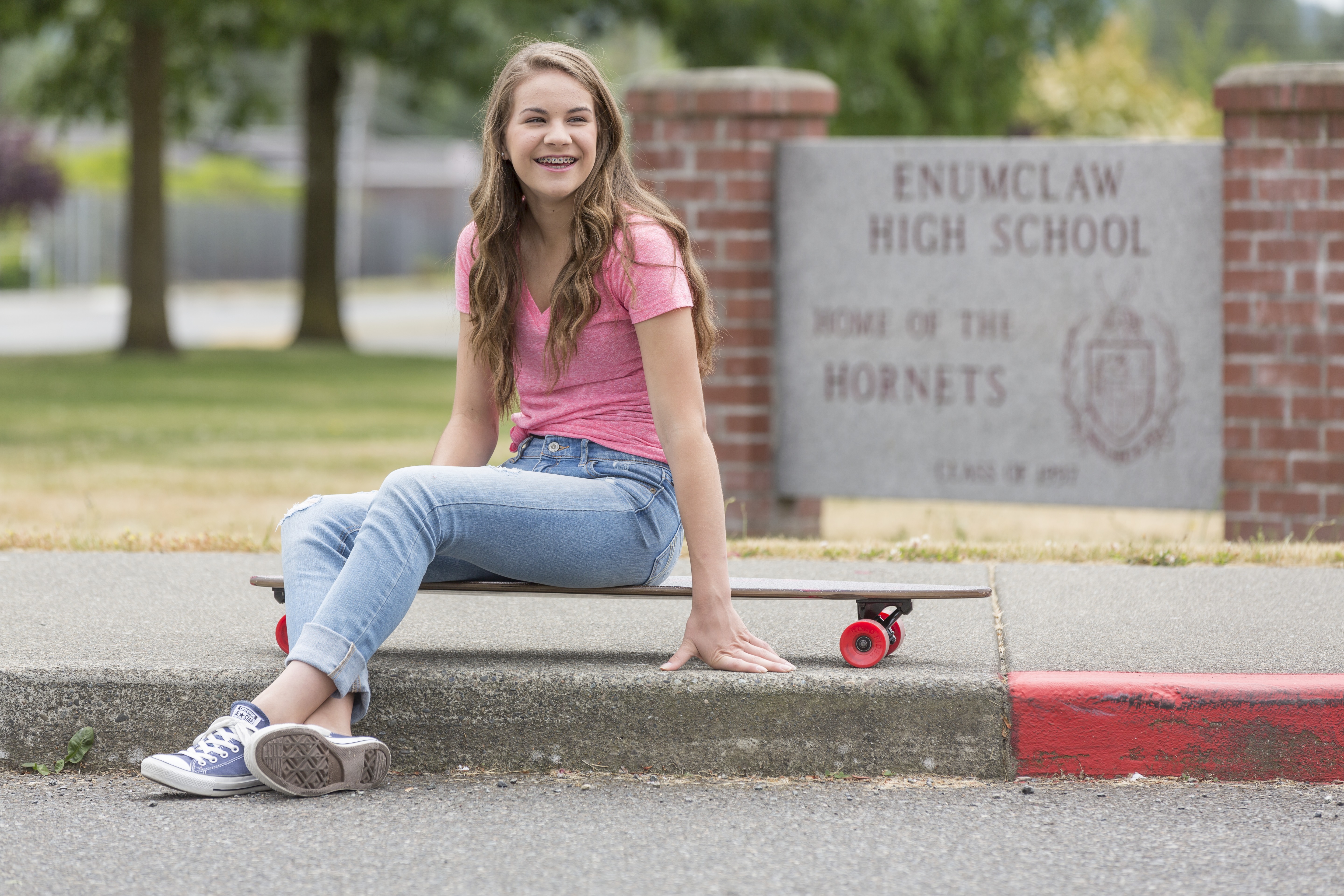 teenage girl outside a school on a skateboard