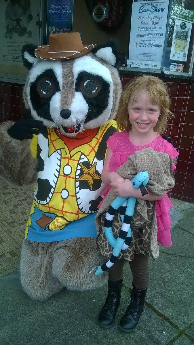 Raccoon mascot posing outside with people