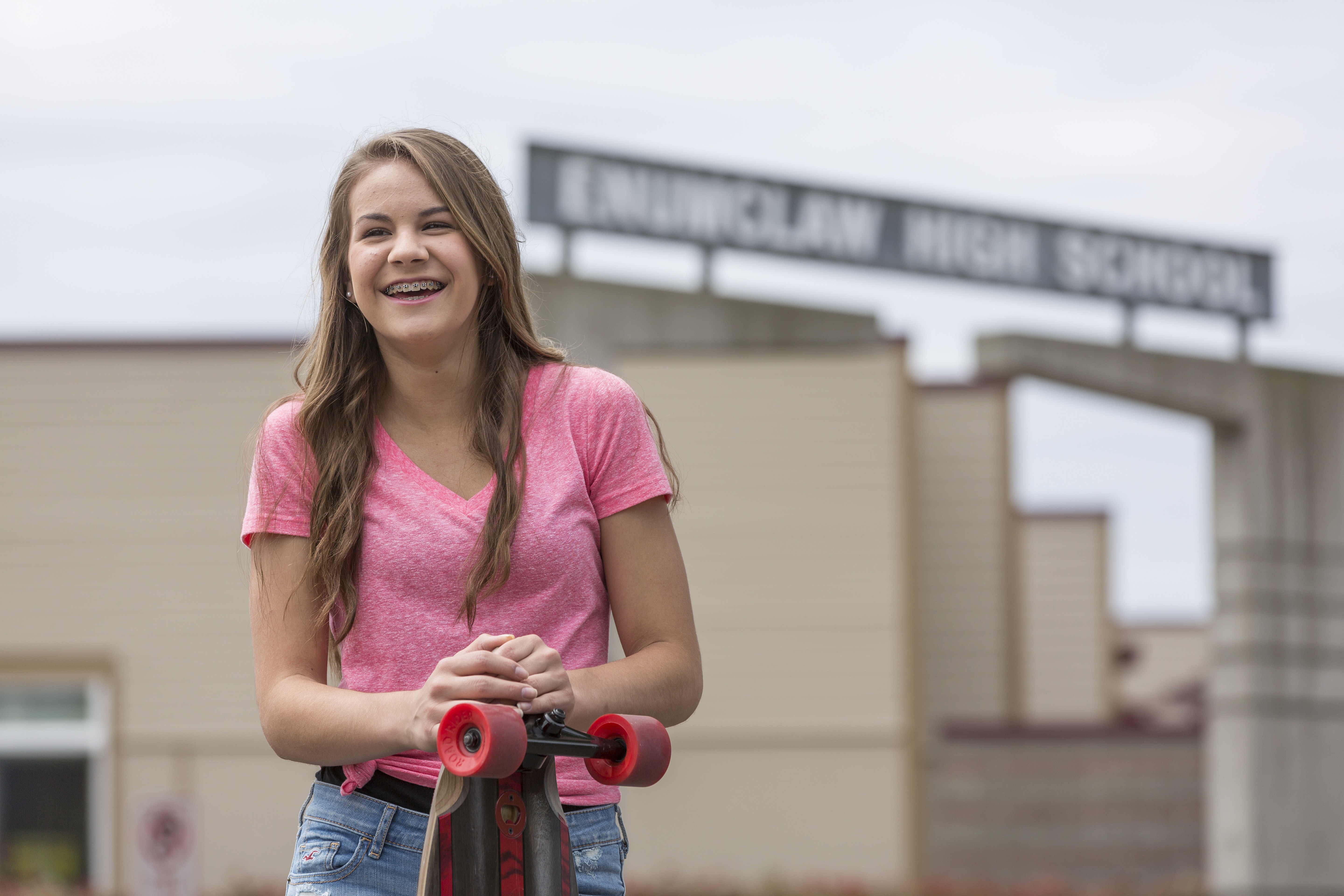 teenage girl smiling and holding a skateboard