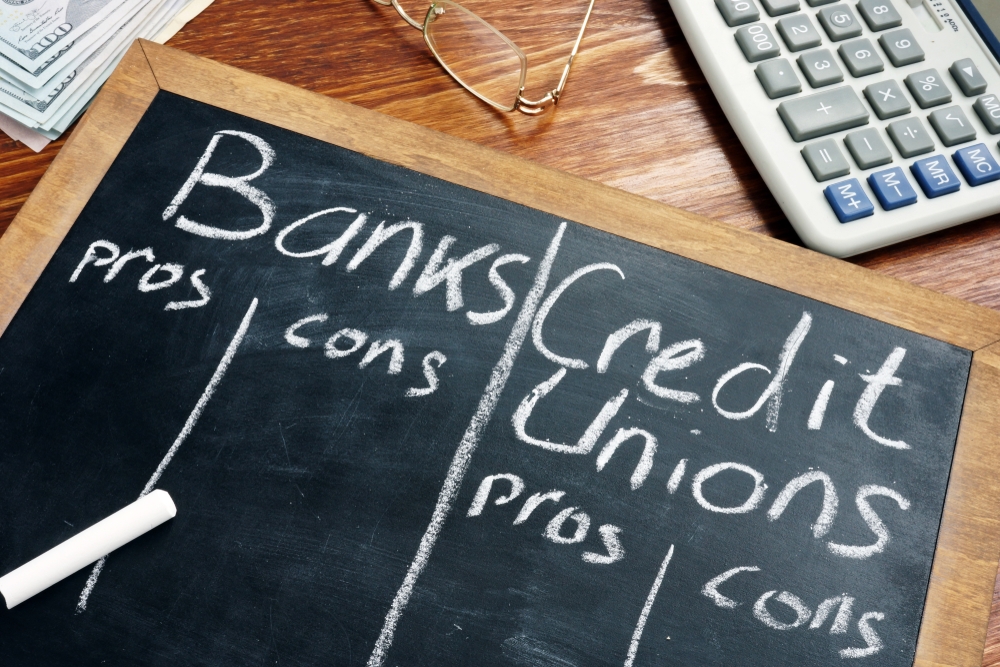 blackboard listing the pros and cons of a credit union over a big bank