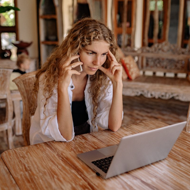 A woman talking on the phone in front of a computer on a blog about phone scams