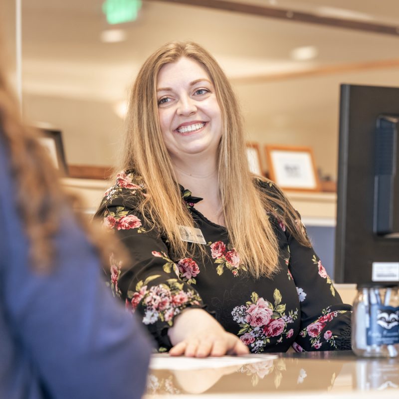 A credit union worker smiling at the person she is helping learn how to use a personal loan