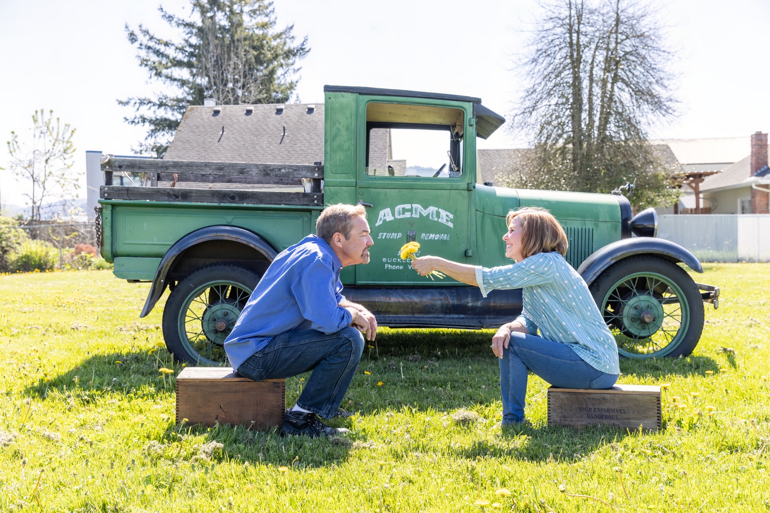 a couple sitting in front of an old green truck smelling flowers and laughing on a blog about saving and spending
