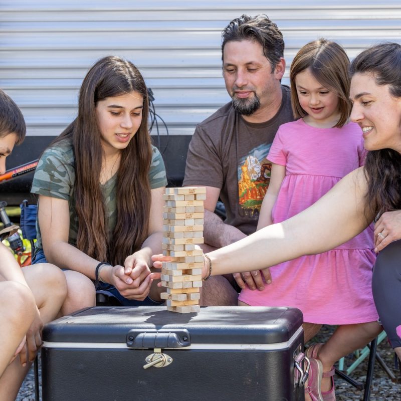 Parents and kids playing Jenga to teach children about money