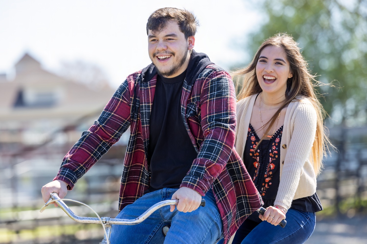 A happy couple laughing and riding a tandem bike on a blog about financial wellness for sweethearts