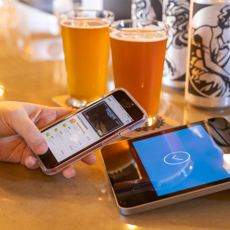 A person using their mobile wallet at a brewery