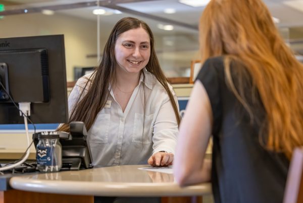 A bank teller helping a member check their credit score to improve credit
