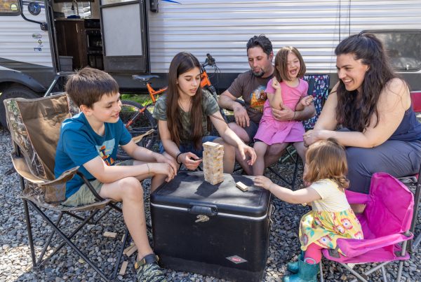 A family playing jenga in front of their RV and discussing back-to-school budget