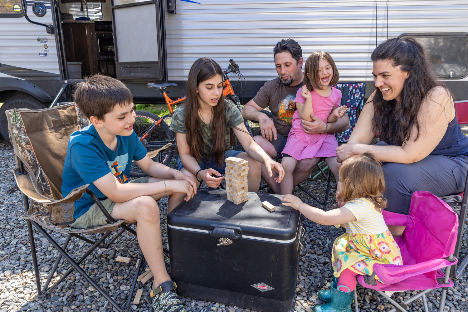 A family playing jenga in front of their RV and discussing back-to-school budget